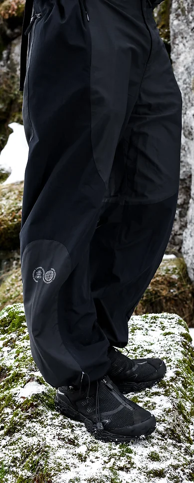 Man wearing black outdoor trousers, standing on a rock