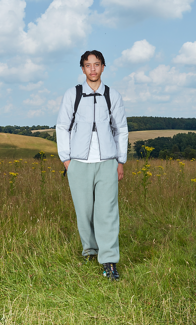 Man wearing a grey jacket and trousers standing in a field