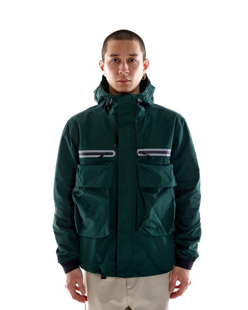 Model wearing Climate Hooded Jacket – Pine Green with bellowed chest pockets. Technical hooded jacket with 3M reflective detailing and water resistance