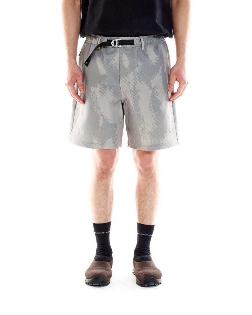 Model wearing PMO Trek Short in concrete camo with built-in belt. Outdoor-ready shorts with front pockets and rear zip pocket.