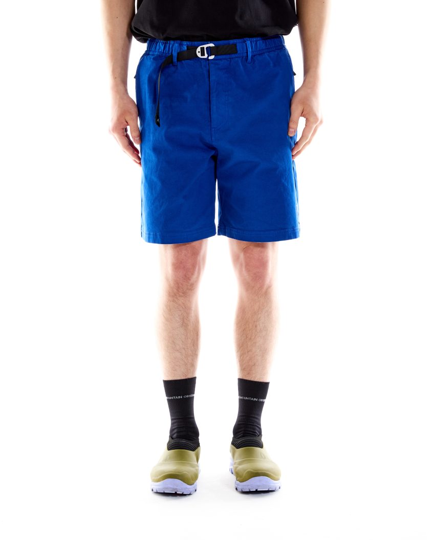 Model wearing Trek Shorts Cobalt with built-in belt and cotton construction. Outdoor shorts designed for comfort, movement, and trail readiness.
